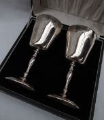 A pair of Elizabeth II silver goblets, decorated with grapes and leaves,