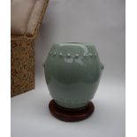 A Chinese celadon vase of barrel shape, with mask and ring handles, with bead decoration,