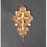 A yellow metal crucifix pendant depicting Christ on the cross to a scrolling wirework and shell
