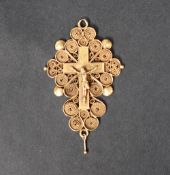 A yellow metal crucifix pendant depicting Christ on the cross to a scrolling wirework and shell