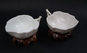A pair of Chinese tea cups of leaf shape, with as flower and leaf moulded foot on wooden bases,