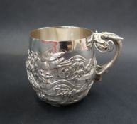 A Japanese silver mug, decorated with birds amongst waves, with a dragon handle,