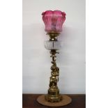 An oil lamp with a graded red to clear glass shade with a clear glass reservoir,