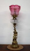 An oil lamp with a graded red to clear glass shade with a clear glass reservoir,