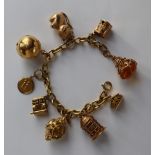 An 18ct yellow gold oval link bracelet, set with numerous 9ct yellow gold charms including a castle,