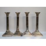 A set of four electroplated on copper Corinthian column candlesticks with stop fluted columns on a