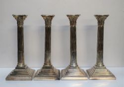 A set of four electroplated on copper Corinthian column candlesticks with stop fluted columns on a