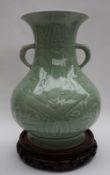 A Chinese celadon vase, with a flared neck and a twin handled baluster body on a spreading foot,