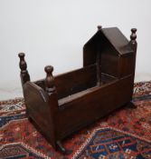 An 18th century oak cot, with a pointed arched top and turned finials, above slat sides on rockers,