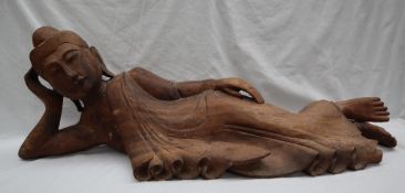 A carved hardwood recumbent buddhistic figure, in traditional dress,