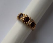 An 18ct yellow gold ruby and diamond Gypsy ring set with three oval faceted rubies and six round