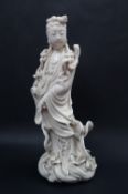 A Chinese Blanc de Chine figure Guanyin, standing on an oval shaped base,