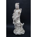 A Chinese Blanc de Chine figure Guanyin, standing on an oval shaped base,