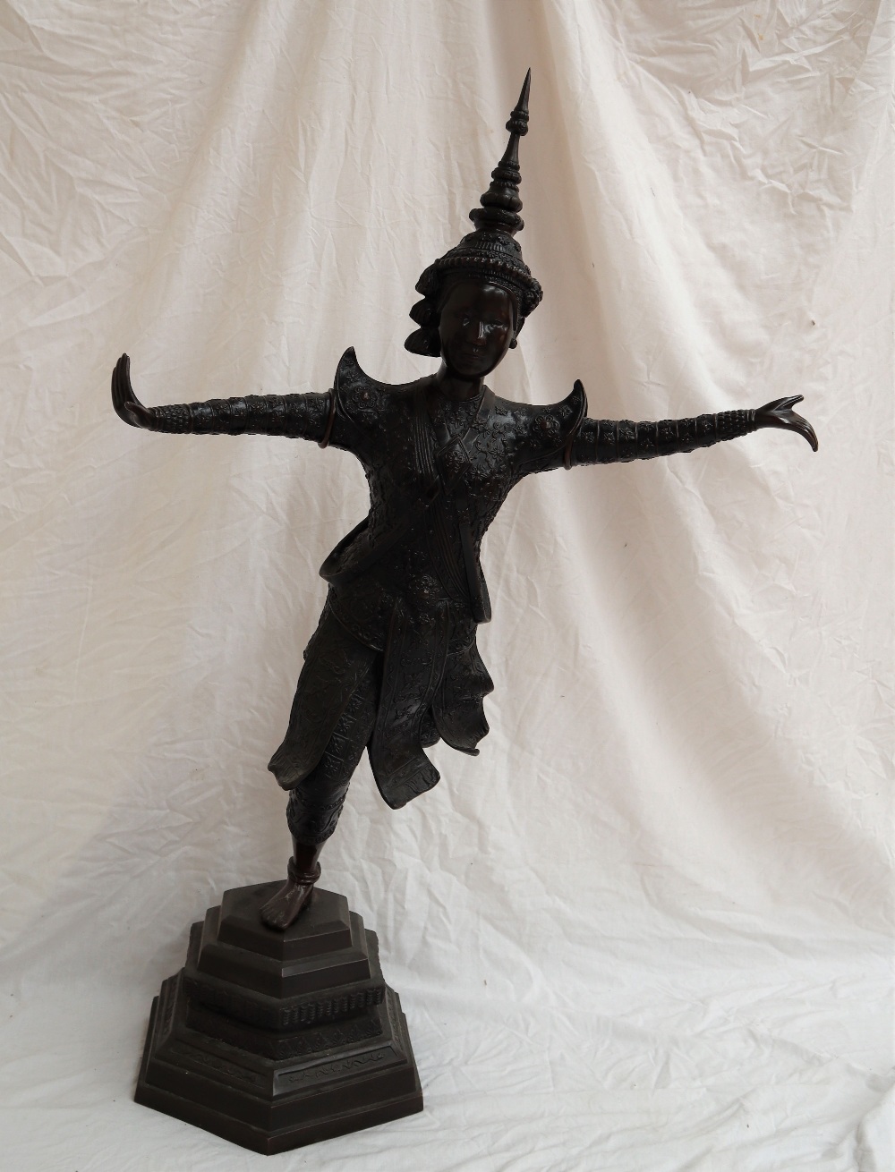 A large bronze figure of a Taiwanese dancer, standing on one leg with arms outstretched ,