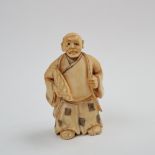 A late 19th /early 20th century Japanese ivory netsuke, depicting a robed figure holding a fan,