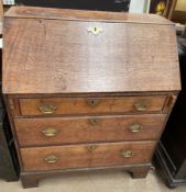 A George III oak bureau with a sloping fall and fitted interior above three long drawers