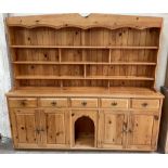 A large pine dresser, with a shaped cornice above two shelves, the base with five drawers,