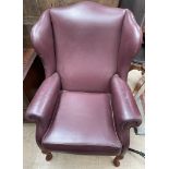 A maroon leather wing back chair on cabriole legs and pad feet