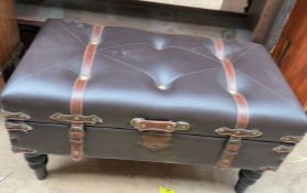 A brown leatherette hinged trunk coffee table on turned legs