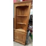 A 20th century pine standing corner cupboard with a moulded cornice above two shelves and a