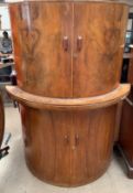 A Art Deco inspired walnut drinks cabinet, of D shape, the top doors enclosing a mirrored interior,