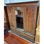 An Edwardian mahogany triple wardrobe, the moulded cornice above a central mirrored door,