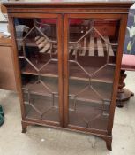 A 20th century mahogany display cabinet with a pair of glazed door on bracket feet