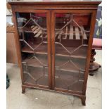 A 20th century mahogany display cabinet with a pair of glazed door on bracket feet