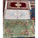 A red ground Chinese rug together with a blue ground example and a green ground rug