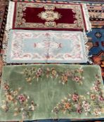 A red ground Chinese rug together with a blue ground example and a green ground rug