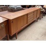 A mid 20th century teak sideboard with a bank of four drawers to the centre and cupboards with