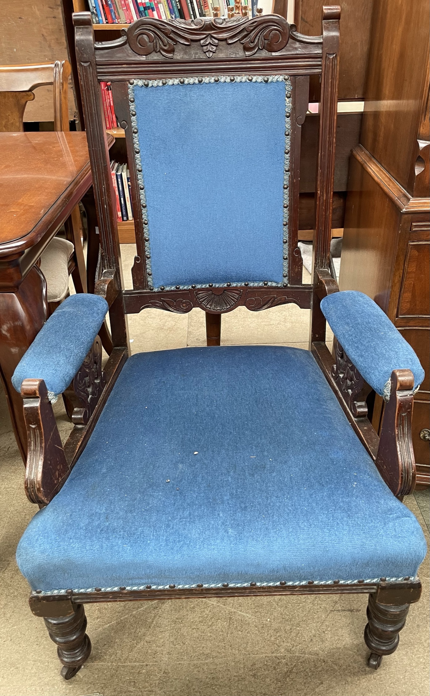 An Edwardian carved gentleman's chair with a pad upholstered back and seat on turned legs