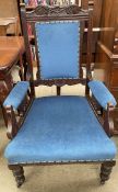 An Edwardian carved gentleman's chair with a pad upholstered back and seat on turned legs