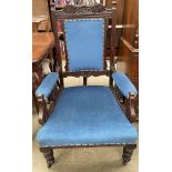 An Edwardian carved gentleman's chair with a pad upholstered back and seat on turned legs