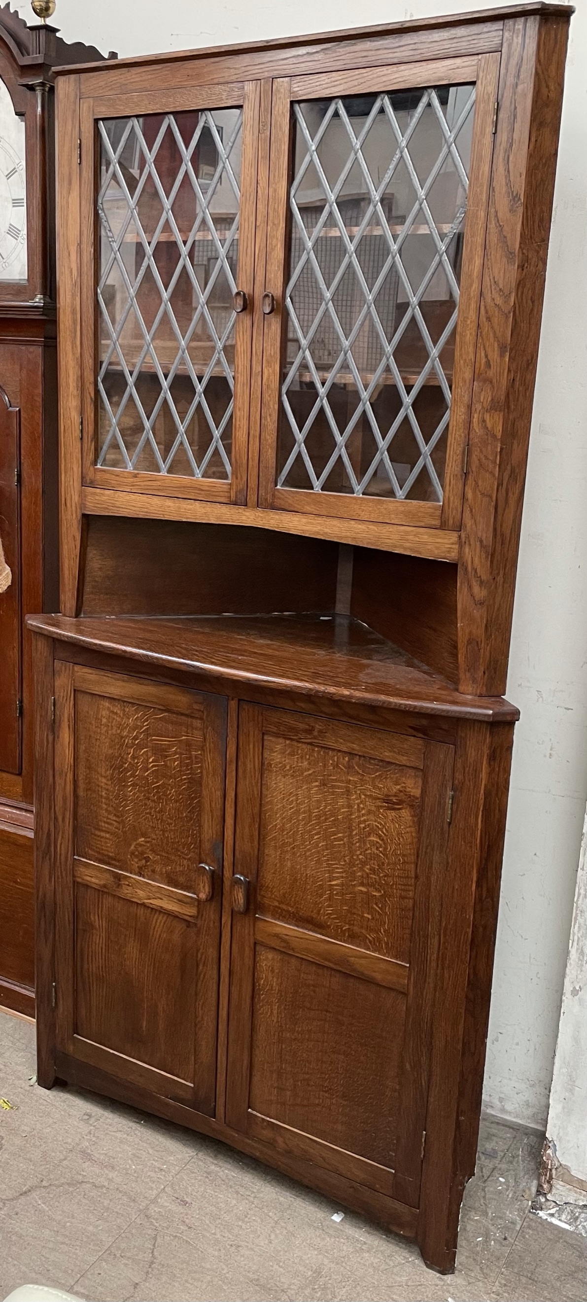 A 20th century oak standing corner cupboard with a leaded glass top,