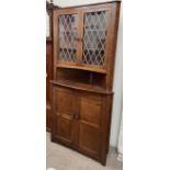 A 20th century oak standing corner cupboard with a leaded glass top,