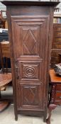 A French oak hall robe with a carved panel door on turned legs,
