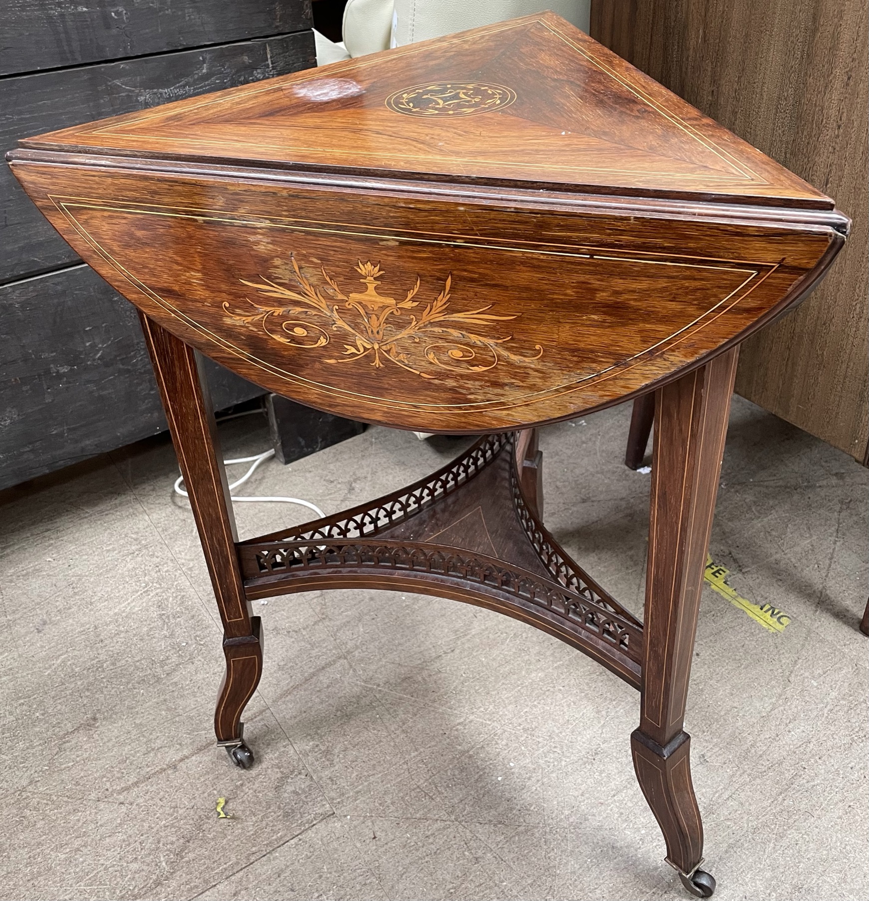 A Victorian inlaid rosewood table of triangular shape with drop flaps on three legs united by an