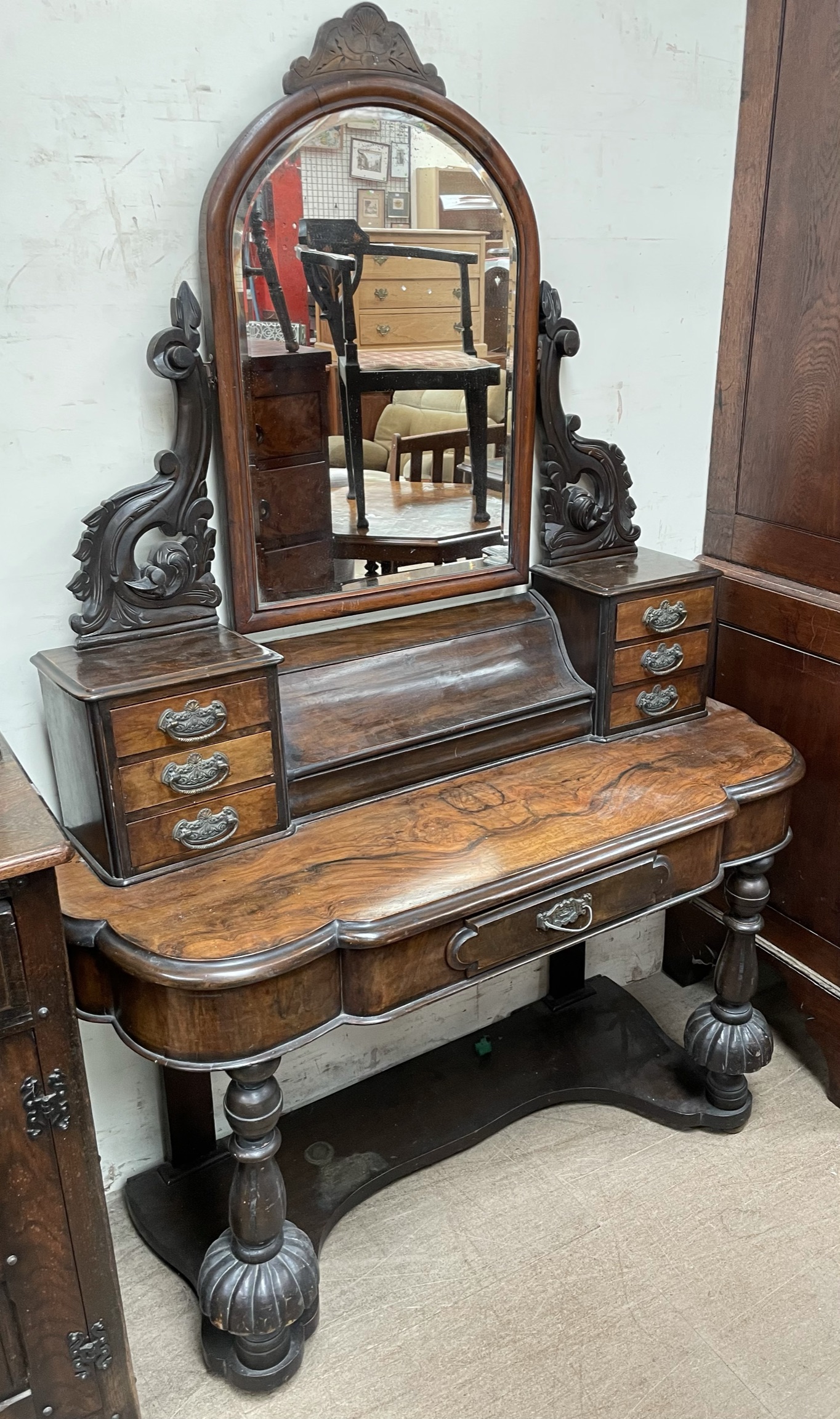 A Victorian walnut dressing table with an arched mirror, piano front compartment and six drawers,