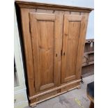A pine linen cupboard, with shelves to one side and hanging space to the other,