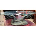 An oval glass topped coffee table held aloft by a pair of mermaids