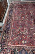 A large red ground rug, with interlocking flower heads and leaves to multiple guard stripes,