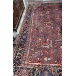 A large red ground rug, with interlocking flower heads and leaves to multiple guard stripes,