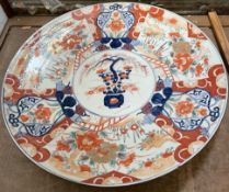 A large Japanese Imari charger decorated with a central vase of flowers