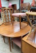 A mid 20th century teak dining suite, comprising a circular dining table with drop flaps,