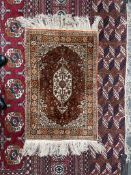 A small Persian silk rug, with a cream ground, central medallion and guard stripes,