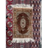 A small Persian silk rug, with a cream ground, central medallion and guard stripes,