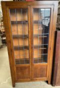 A 20th century oak bookcase with a pair of leaded glass doors on stiles,