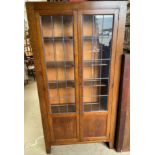 A 20th century oak bookcase with a pair of leaded glass doors on stiles,