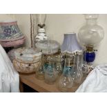 An oil lamp with a blue glass reservoir, together with other oil lamps, glass lamp shades,